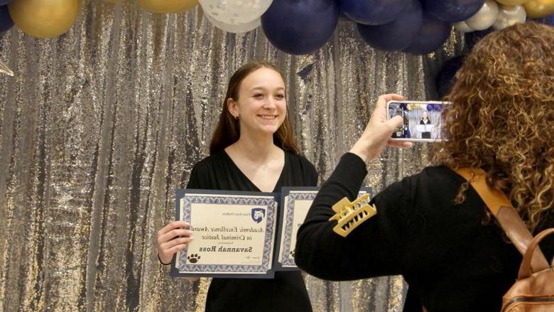 Penn State 杜波依斯 student Savannah Ross pauses with her awards for a photo, taken by a family member, at the recognition and awards banquet at the PAW Center.